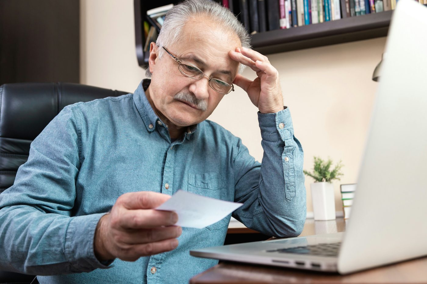 Senior man carefully reviewing his smartphone with reading glasses